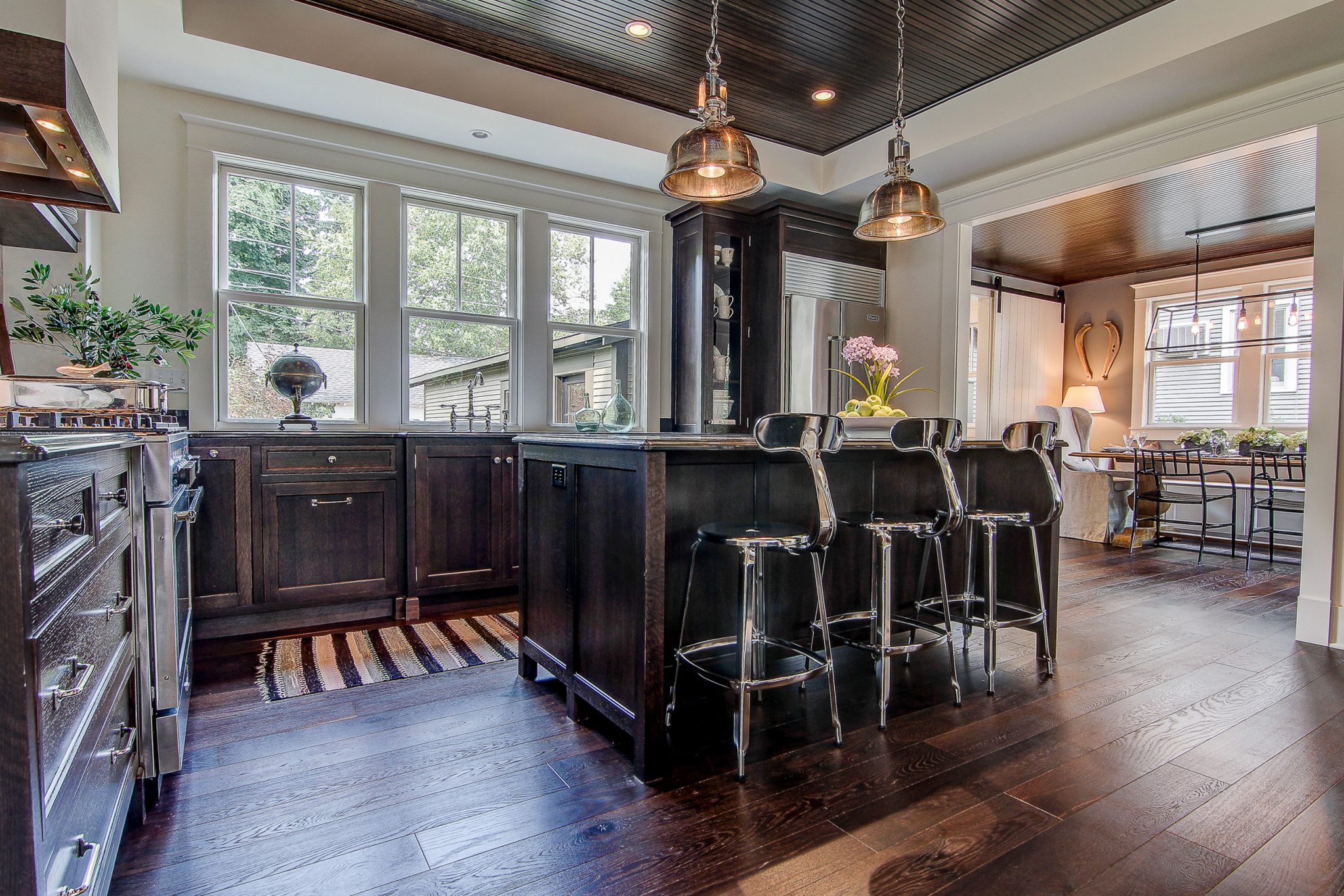 Kitchen with dark stained oak cabinets and island with three bar stools