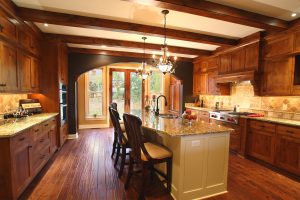 Kitchen with wood beams and knotty alder cabinets with a large painted island