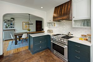 Kitchen with painted cabinets and a stained rustic tapered wood hood