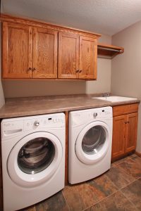 Laundry room with rustic oak cabinets, laminate countertop and hanging rod and shelf