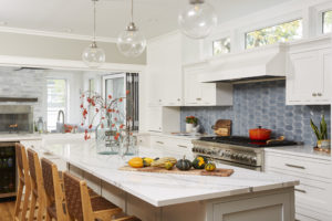 kitchen with painted white cabinets, blue tile backsplash and island